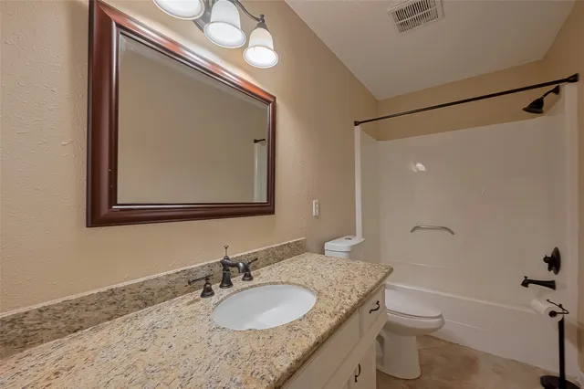 a bathroom with a granite countertop sink a toilet and a mirror