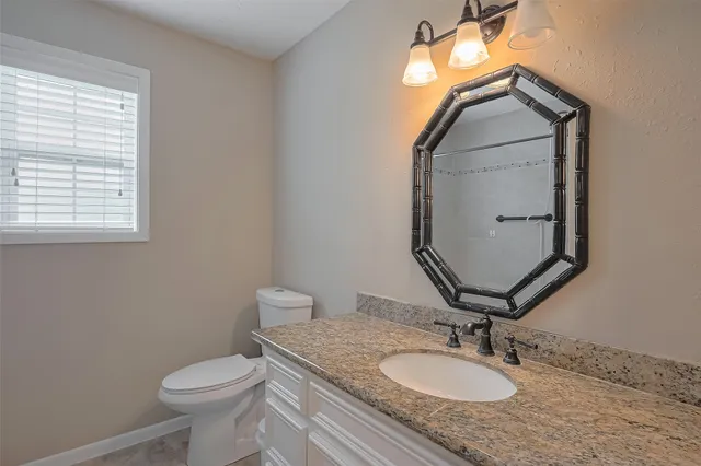 a bathroom with a toilet sink vanity and mirror
