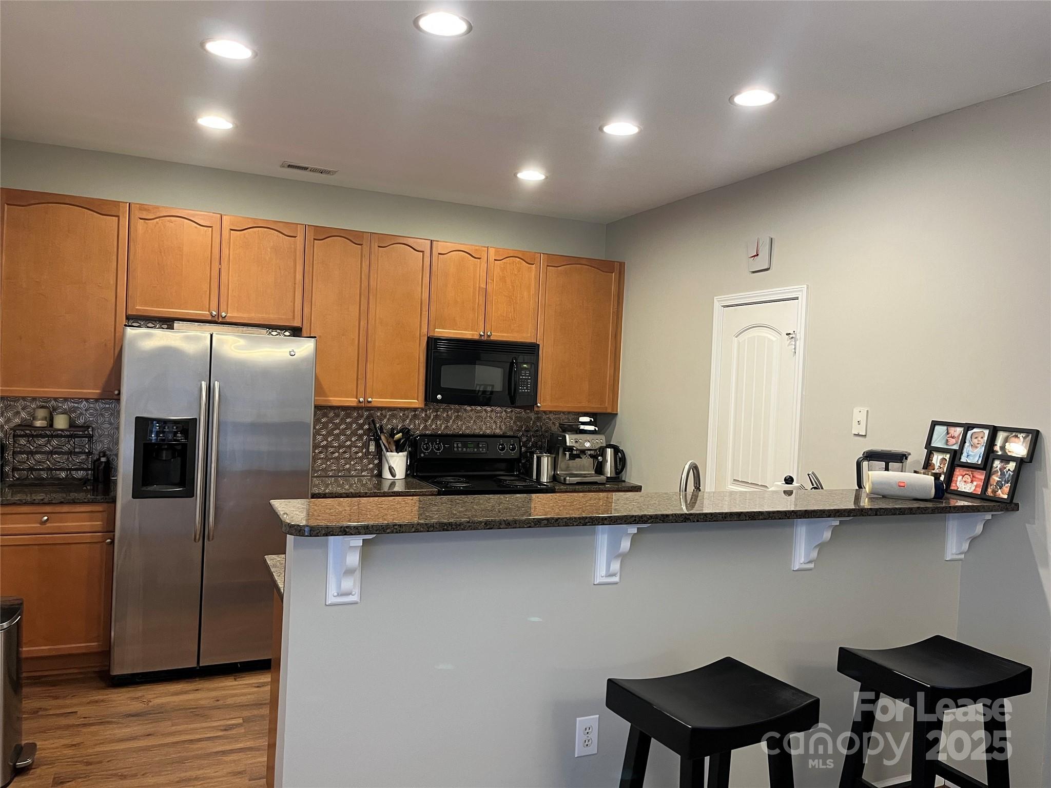 1131 Central Park Circle Davidson, NC 28036 - Photo 13 of 21 a kitchen with stainless steel appliances a sink a stove a refrigerator a microwave oven with white cabinets and wooden floor