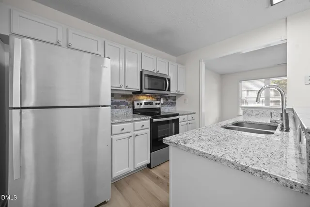 a kitchen with granite countertop a refrigerator stove and sink