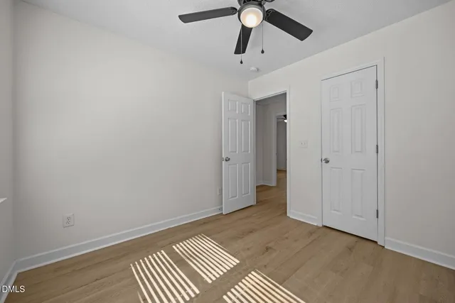 an empty room with closet and a chandelier fan