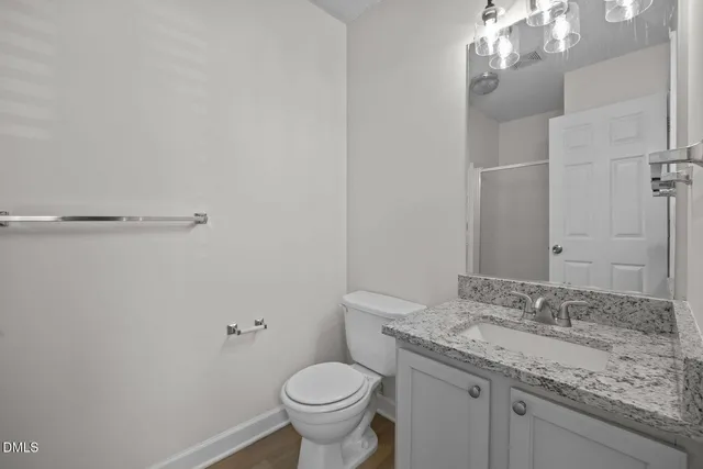 a bathroom with a granite countertop sink a toilet and a mirror