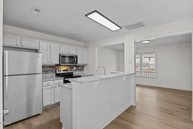 a kitchen with a refrigerator a stove top oven a sink and dishwasher with wooden floor