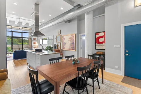 a dining room with stainless steel appliances kitchen island granite countertop a dining table chairs and a large window
