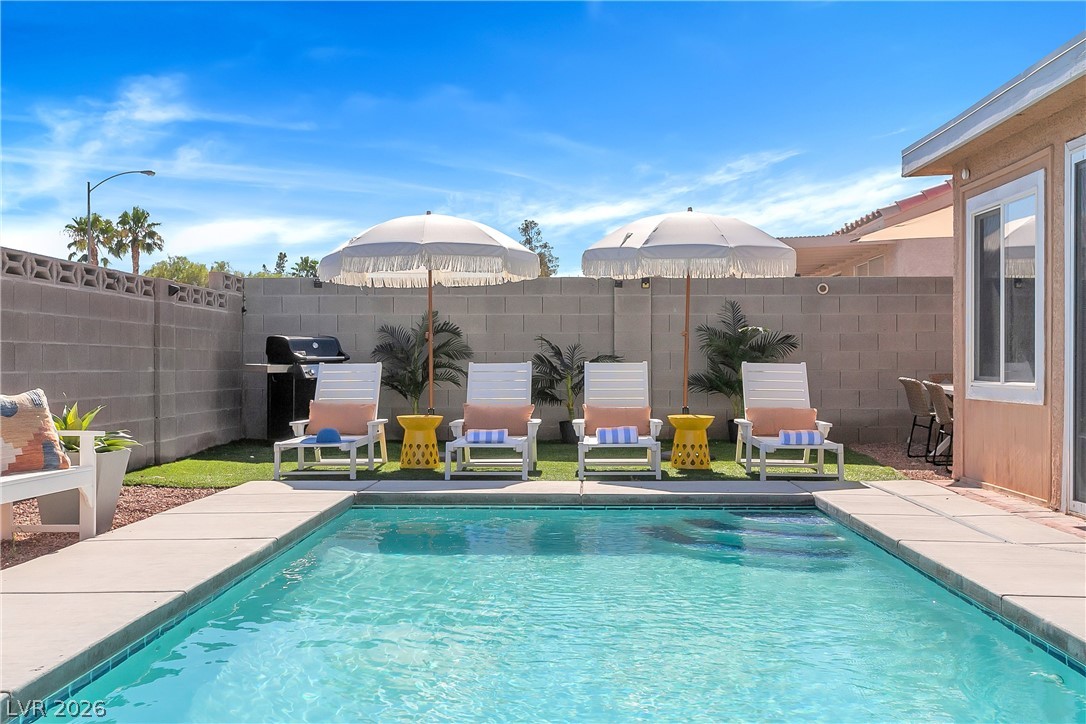 101 Beaver Ridge Avenue North Las Vegas, NV 89031 - Photo 32 of 42 An inviting backyard oasis offers a crystal-clear pool, a cozy patio area, and lush green space.