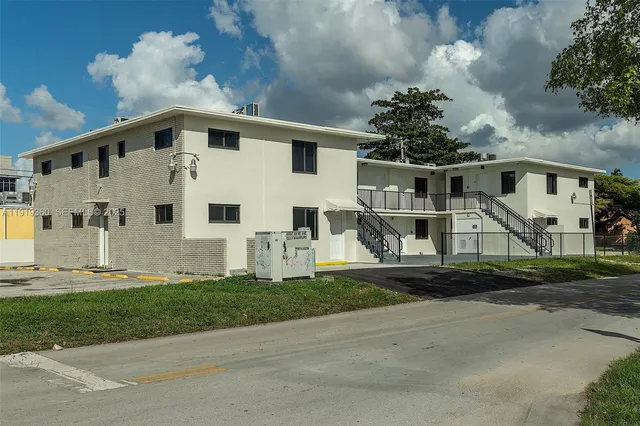 a view of a white house next to a yard with big trees