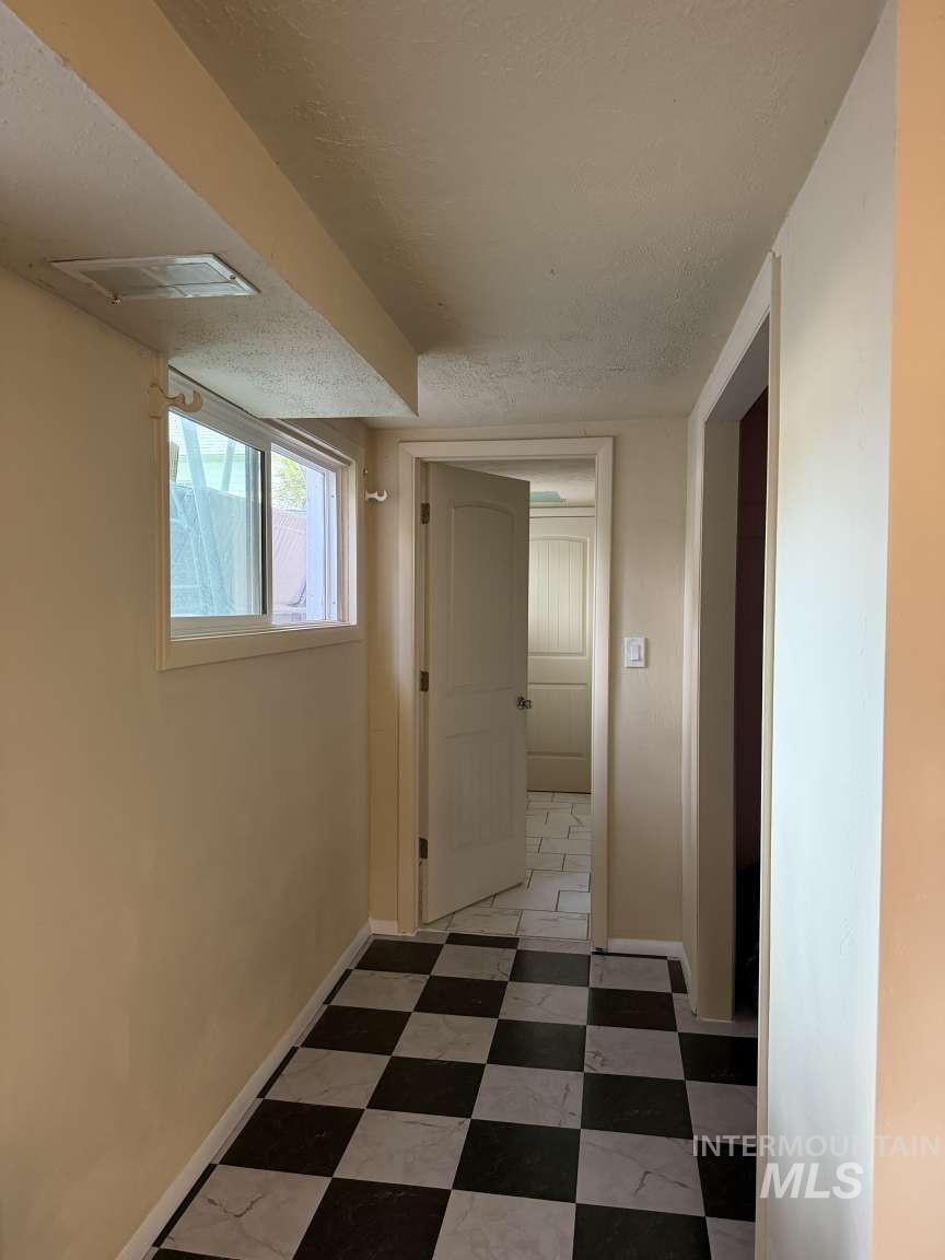 1158 South Powerline Road Nampa, ID 83686 - Photo 45 of 46 Hallway featuring black and white checkered flooring, a window providing natural light, and a white interior door