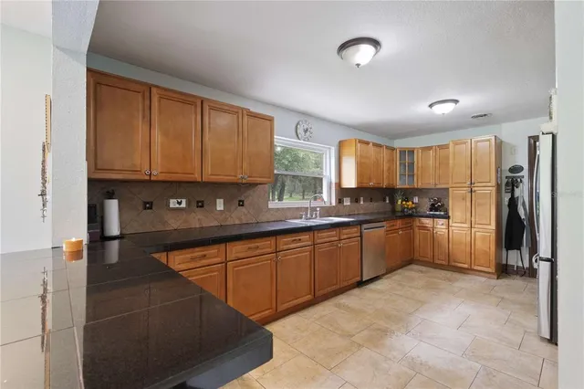 a large kitchen with stainless steel appliances granite countertop a stove a sink and a refrigerator