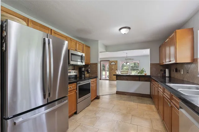 a large kitchen with stainless steel appliances granite countertop a refrigerator oven a sink dishwasher and wooden cabinets