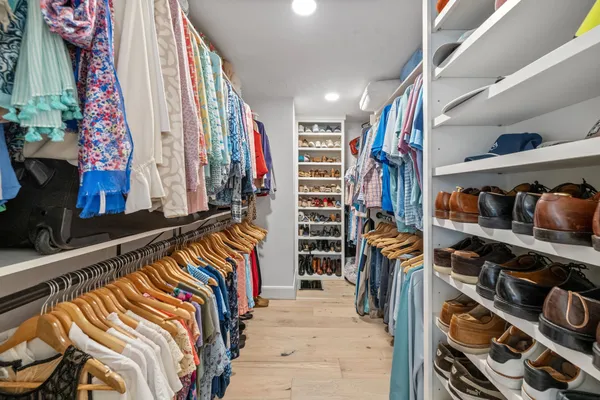 a view of walk in closet with clothes and shoes