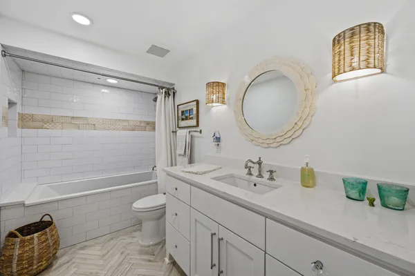a bathroom with a granite countertop sink a toilet a mirror and shower