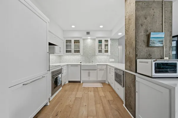 a view of a kitchen with a sink wooden floor and stainless steel appliances