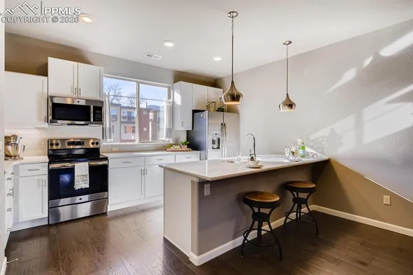 a kitchen with stainless steel appliances a sink a stove a refrigerator and chairs