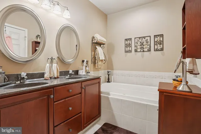 a bathroom with a granite countertop tub a double vanity sink and a mirror