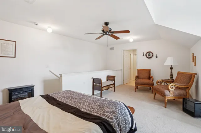 a bedroom with a bed a chair and potted plant on the dresser