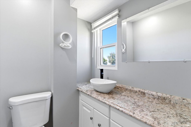 1613 Sunset Road Lake Point, UT 84074 - Photo 14 of 33 Bathroom featuring a vanity with a vessel sink, light-toned countertop, and white cabinetry