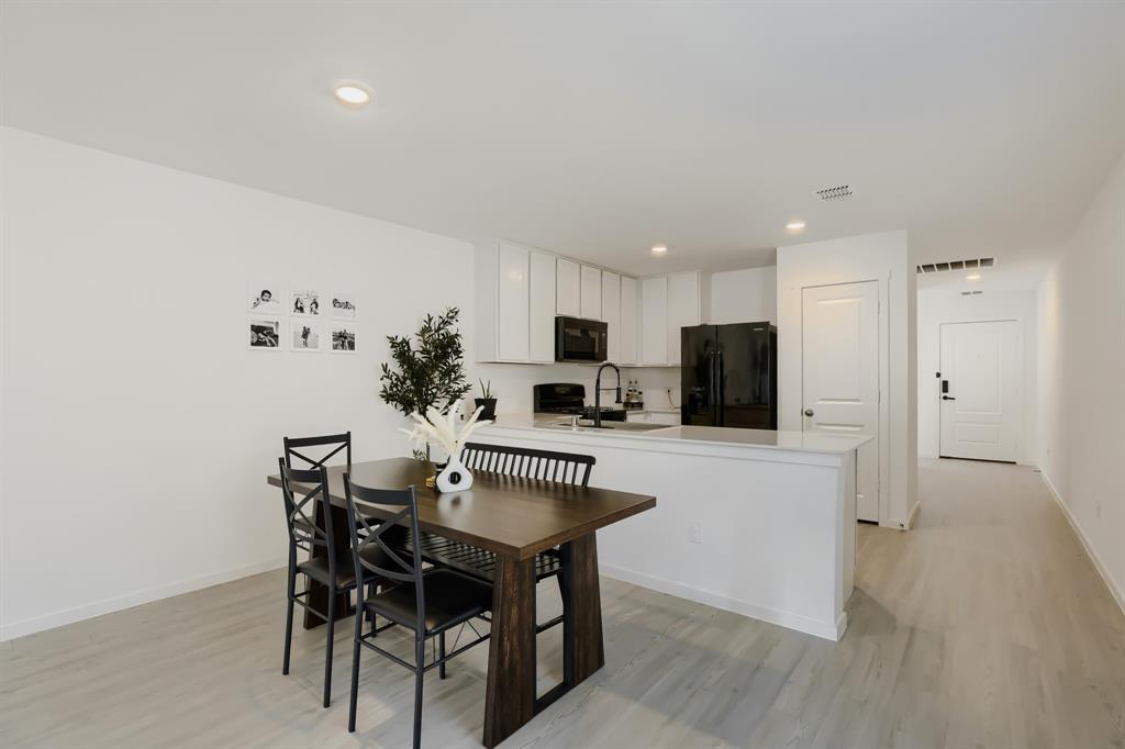 1619 Grassy Pond Road Forney, TX 75126 - Photo 16 of 28 Light wood-finish flooring, white walls, recessed lighting, and a kitchen featuring white cabinetry, a white countertop, and black appliances