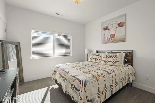 a bedroom with a bed and a flat tv screen on a dresser