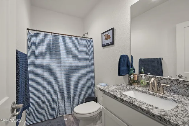 a bathroom with a granite countertop toilet a sink and mirror