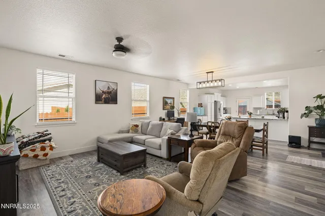 a living room with furniture potted plant and open kitchen view
