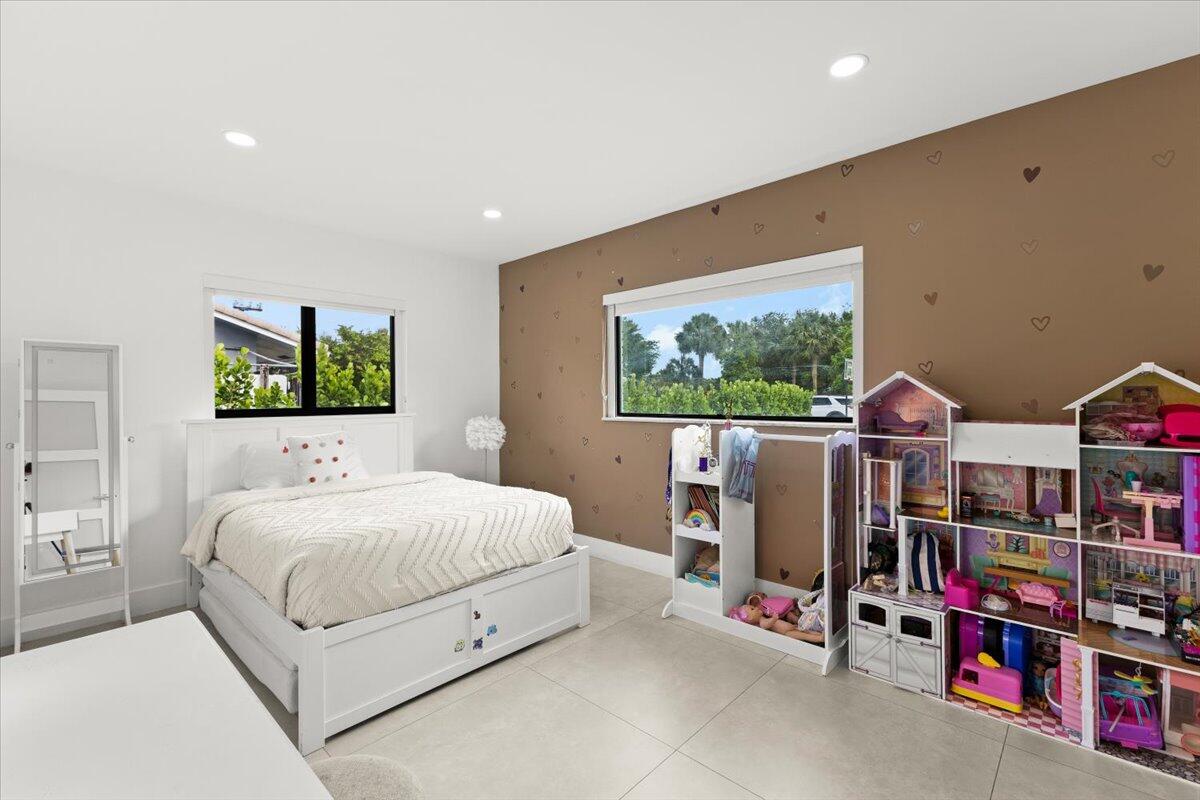 1049 West Palmetto Park Road Boca Raton, FL 33486 - Photo 22 of 40 a bedroom with a bed a bookshelf and a flat screen tv