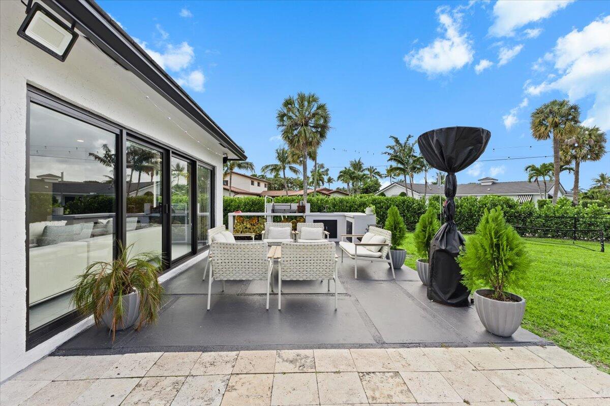 1049 West Palmetto Park Road Boca Raton, FL 33486 - Photo 28 of 40 a view of a patio with a table and chairs potted plants with wooden floor and fence