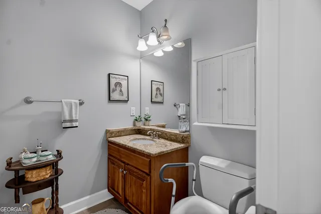 a bathroom with a granite countertop toilet a sink and mirror