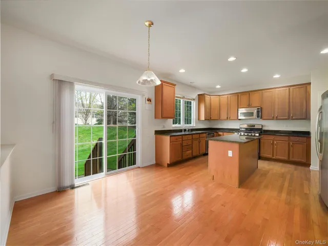 a kitchen with stainless steel appliances granite countertop a sink a stove and a wooden floors