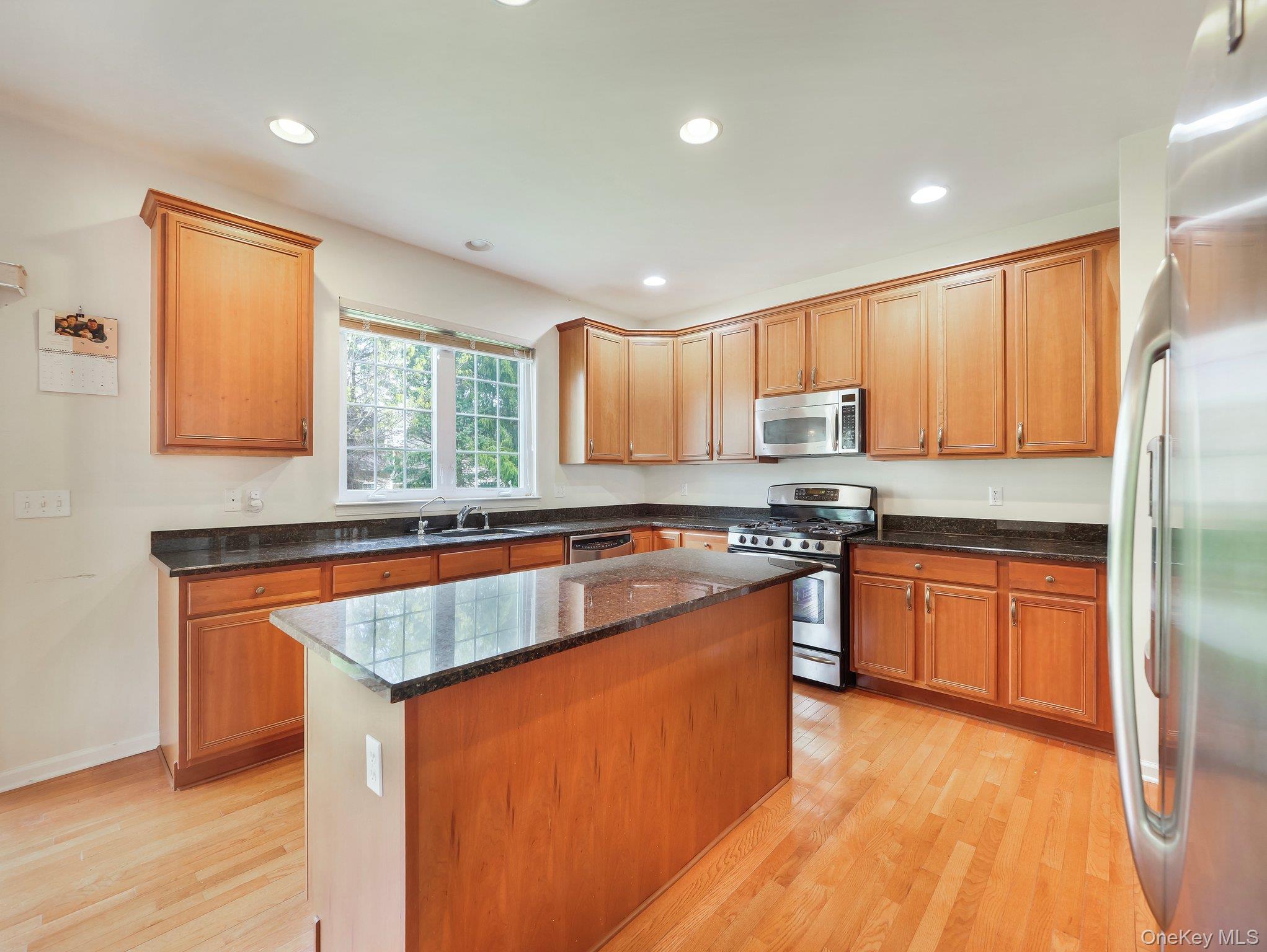 417 Vassar Place Fishkill, NY 12524 - Photo 8 of 38 a kitchen with stainless steel appliances granite countertop a stove a sink dishwasher a refrigerator and a microwave oven with wooden floor