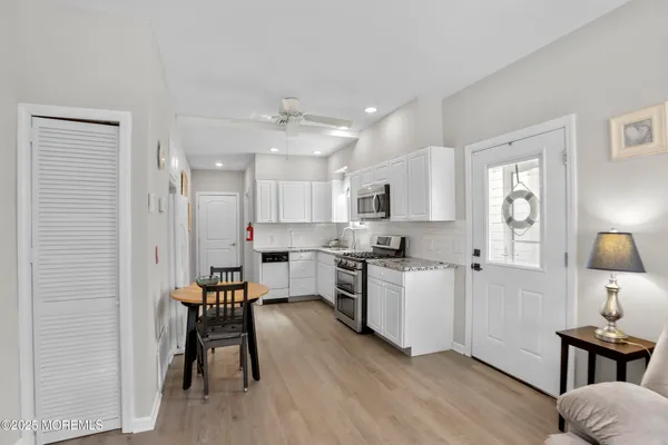 a kitchen with a table chairs refrigerator and wooden floor