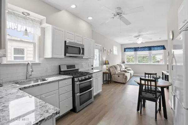 a kitchen with stainless steel appliances granite countertop a stove a sink dishwasher a dining table and chairs with wooden floor