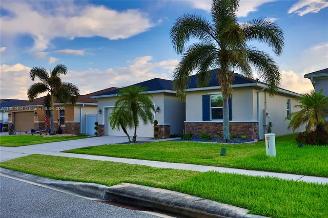 front view of a house with a yard and palm trees