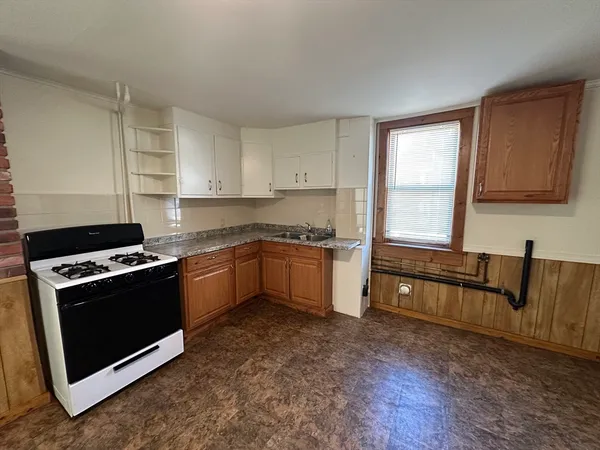 a kitchen with granite countertop a stove a sink and a refrigerator