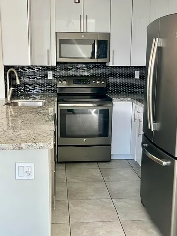a kitchen with granite countertop a stove microwave and refrigerator