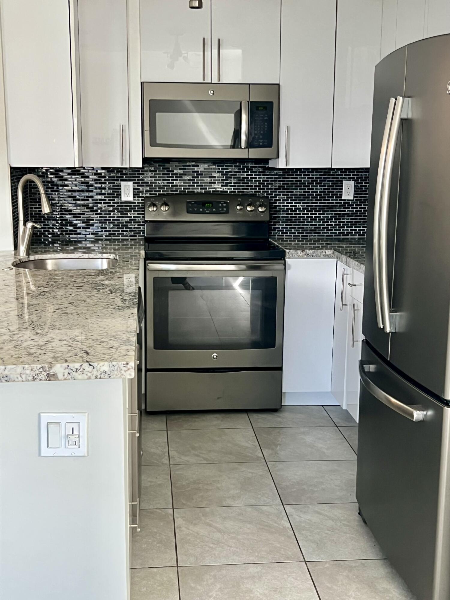 150 Burgandy Way, Unit D Delray Beach, FL 33484 - Photo 6 of 33 a kitchen with granite countertop a stove microwave and refrigerator