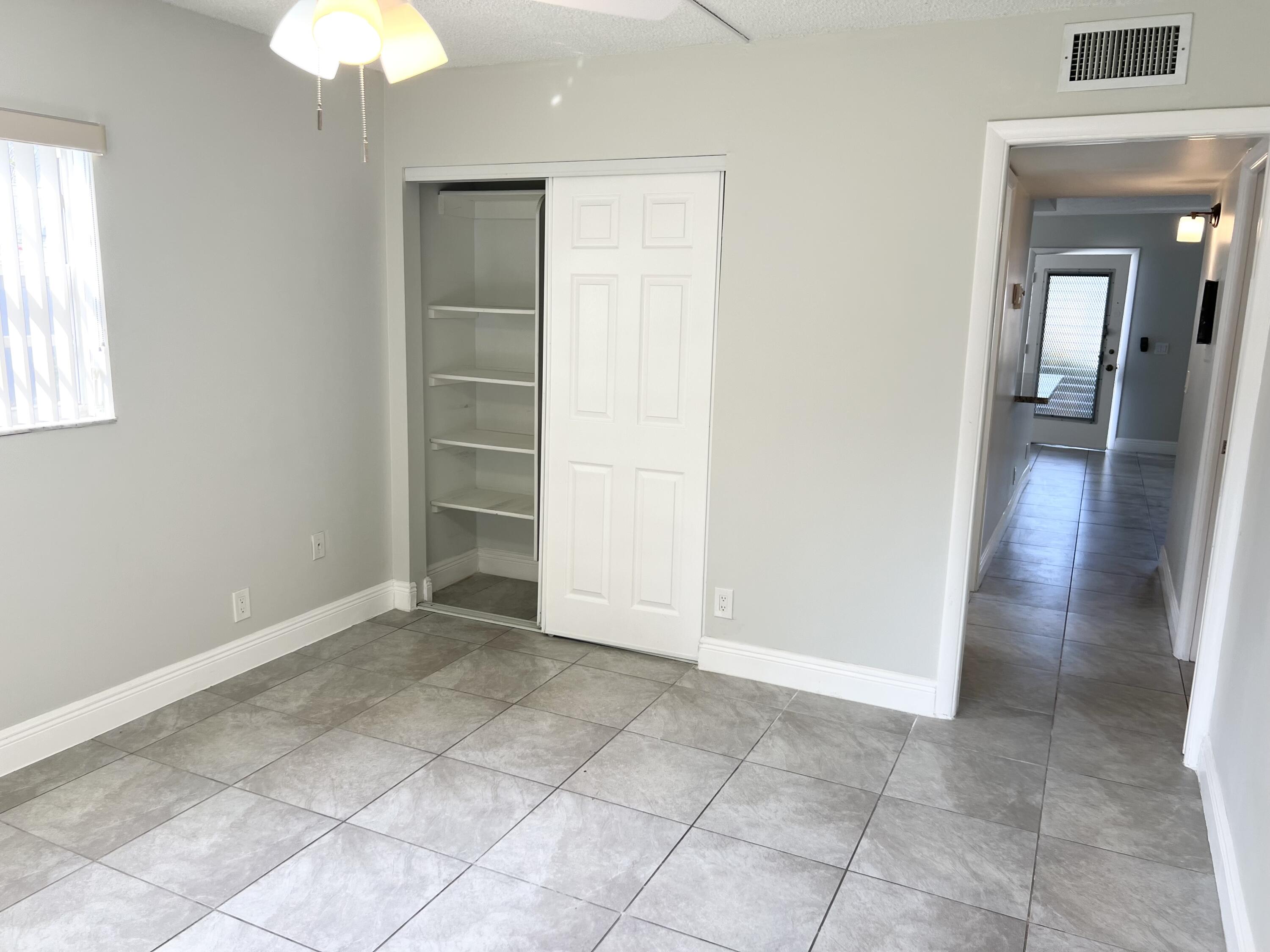 150 Burgandy Way, Unit D Delray Beach, FL 33484 - Photo 10 of 33 an empty room with a fireplace and a chandelier fan