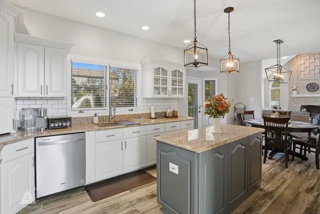 a kitchen with kitchen island granite countertop a sink a counter space appliances and cabinets