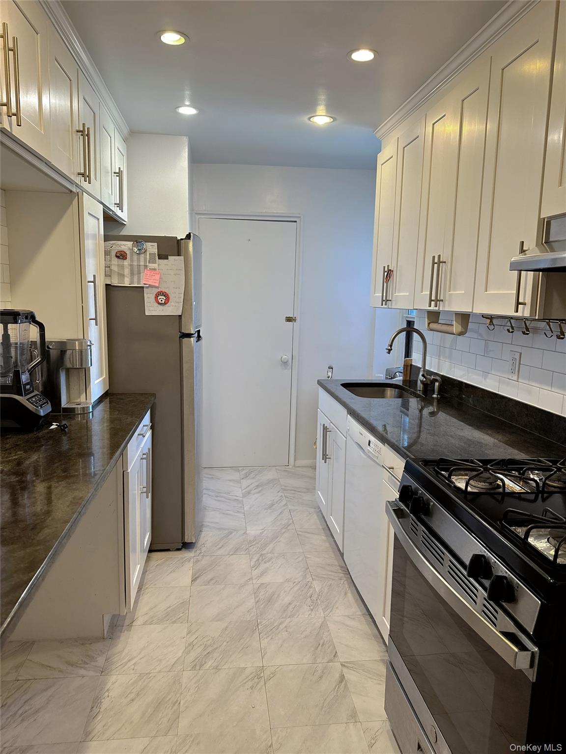 18-40 211th Street, Unit 5A Queens, NY 11360 - Photo 11 of 21 a kitchen that has a sink stainless steel appliances a counter space and a window