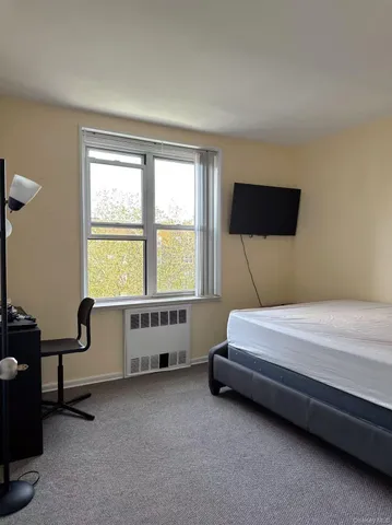 a spacious bedroom with a bed and a flat tv screen on a dresser