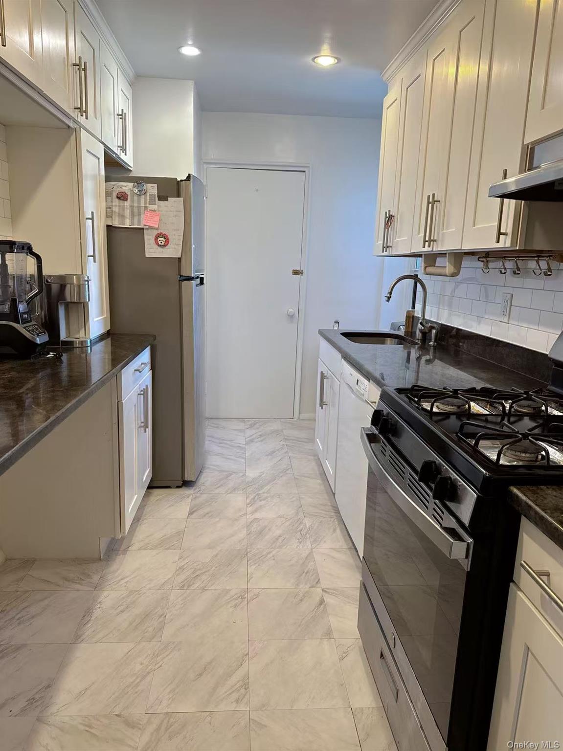 18-40 211th Street, Unit 5A Queens, NY 11360 - Photo 8 of 21 a kitchen with stainless steel appliances granite countertop a stove refrigerator sink and microwave