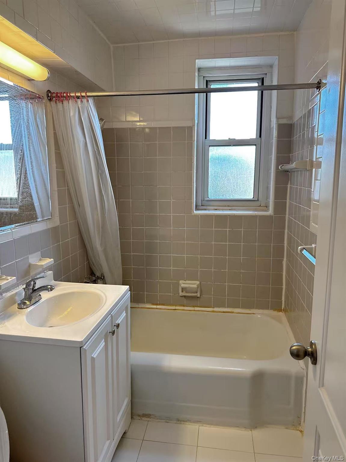 18-40 211th Street, Unit 5A Queens, NY 11360 - Photo 9 of 21 a bathroom with a sink a mirror a bathtub and shower