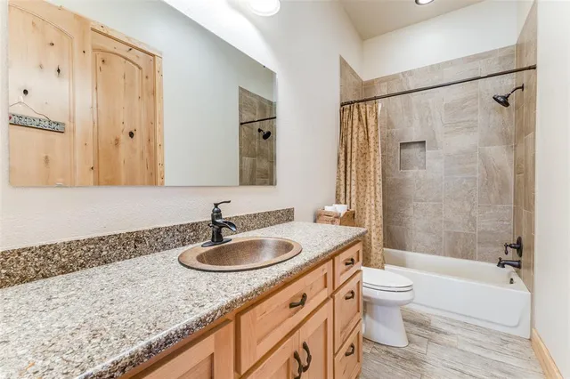 a bathroom with a granite countertop sink a toilet and shower