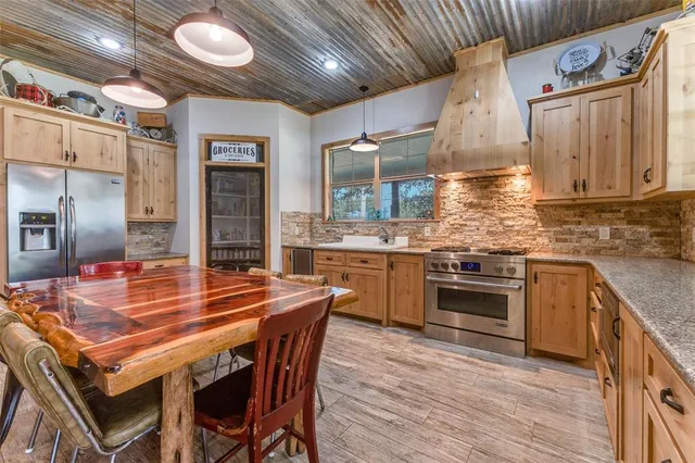 a kitchen with stainless steel appliances kitchen island granite countertop a table chairs sink and cabinets