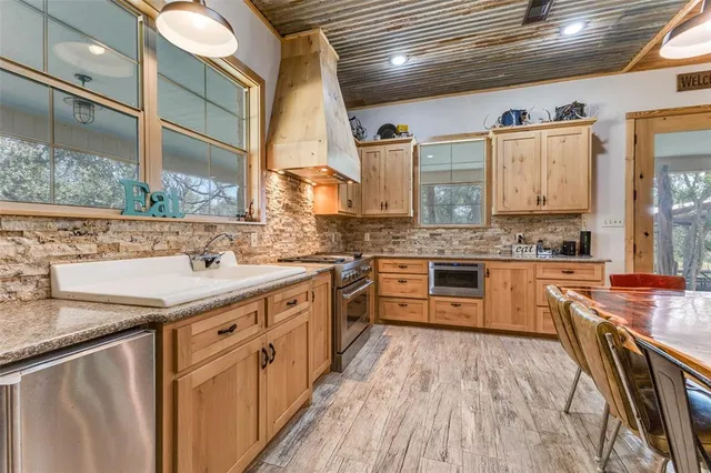 a kitchen with stainless steel appliances granite countertop a sink a stove and a wooden floors