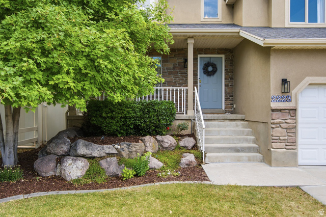 2223 North Pointe Meadow Loop Lehi, UT 84048 - Photo 3 of 56 Stucco and stone facade featuring a light blue entry door with a covered porch