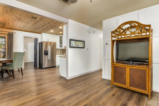 a view of a livingroom with wooden floor and a refrigerator