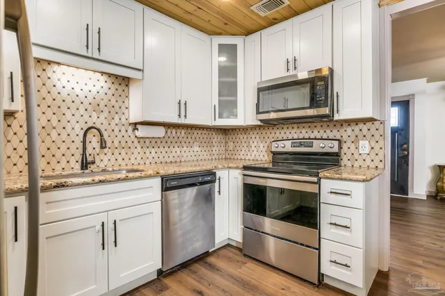 a kitchen with white cabinets stainless steel appliances and sink