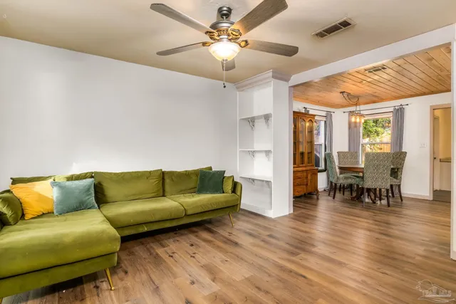a living room with furniture and a dining table with wooden floor