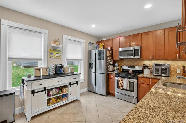 a kitchen with stainless steel appliances kitchen island granite countertop a refrigerator and a stove top oven