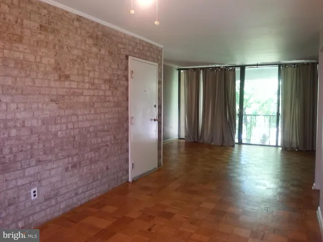 an empty room with wooden floor and windows with curtains